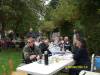 Members sitting at tables under the apple trees eating