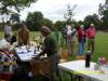 Members sitting at tables under the apple trees eating